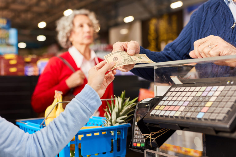 Customer gives cashier a cash receipt as payment at the supermar InsideSources